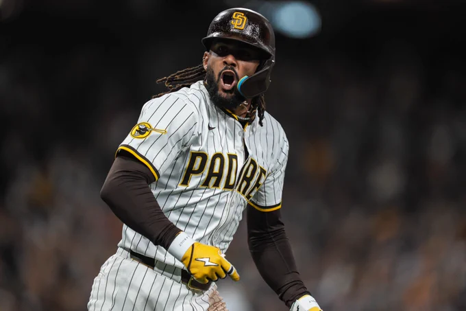 Fernando Tatis Jr. looking toward the dugout yelling in celebration after hitting a home run. 