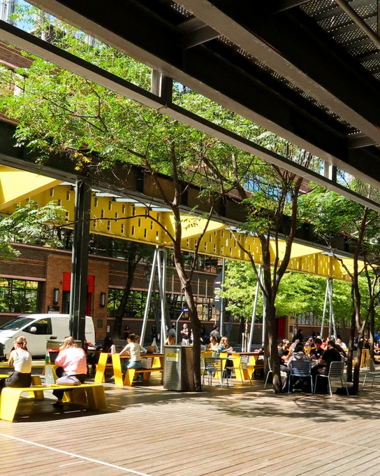 Bowen Street in the sun, there are students at the yellow tables, studying, eating and socialising