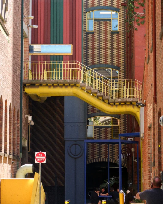 A side building profile, with an iconic yellow staircase and postmodern tiling details. 