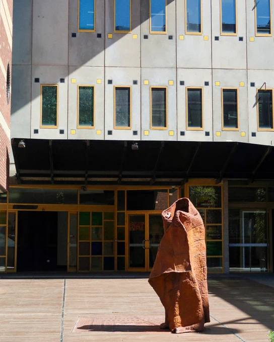 Building 8 exterior from Bowen Street, the Possum Skin Cloak statue is in the sun, in front of the building