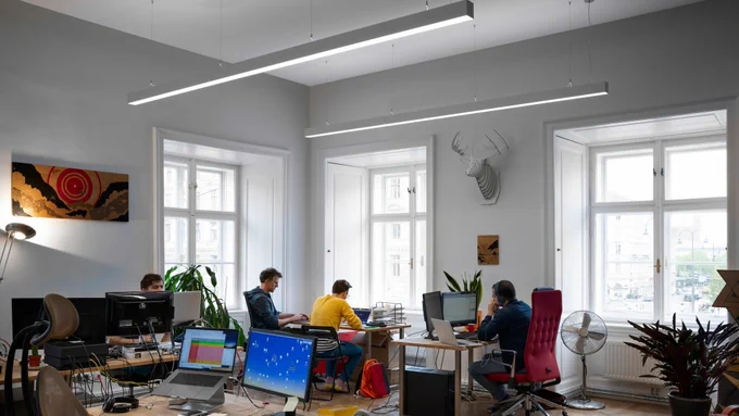 Photo showing 4 people working in the Broken Rules office in Vienna. A brightly-lit, high-ceiling room with 3 big windows.
