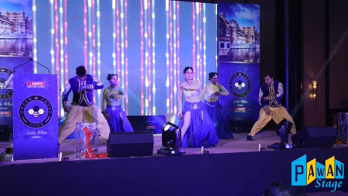 A lively group of dancers on stage at a corporate event gala in Udaipur, captivating the audience with their performance.
