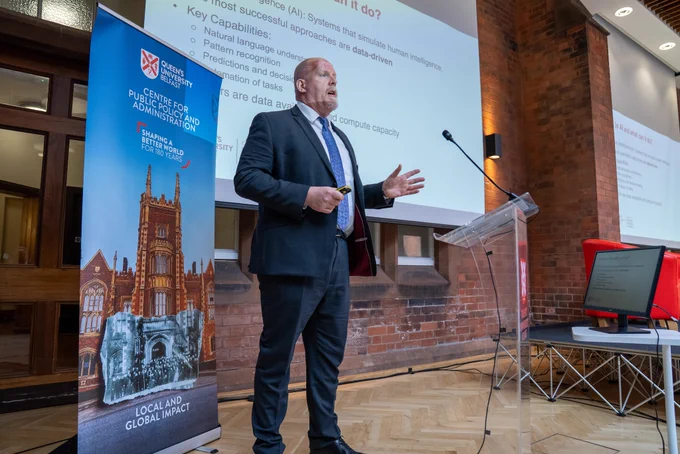 Image shows Professor Iain Styles speaking on stage.