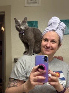 A gray cat sitting on a lady's shoulder.