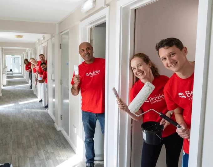 People in red Berkeley Foundation t-shirts painting rooms in a corridor.