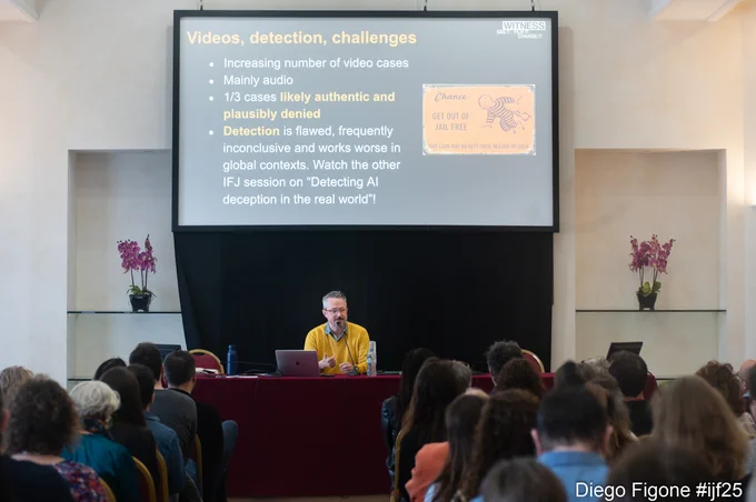 The speaker, Sam Gregory, in a yellow sweater, presents on stage at a conference session during the International Journalism Festival (#ijf25). A projected slide behind him highlights challenges in detecting deceptive media, mentioning audio deepfakes, plausibly denied cases, and flaws in detection tools. The room is full of seated attendees listening attentively. 

Image credit: Diego Figone | International Journalism Festival 2025 (#ijf25)