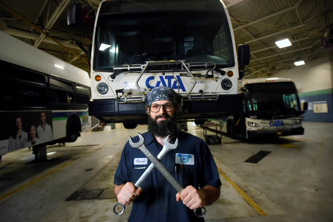 Mechanic posing for a photo in front of the CATA buses. 
