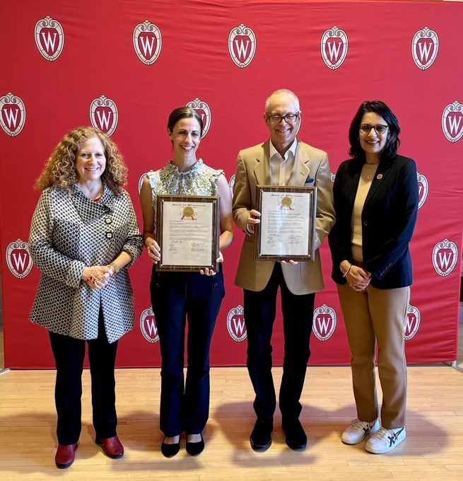 Chancellor Mnookin, DTA awardee Paul Barford, DTA awardee Amy Trowbridge, and Rep. Renuka Mayadev smiling in front of a Wisconsin crest backdrop.