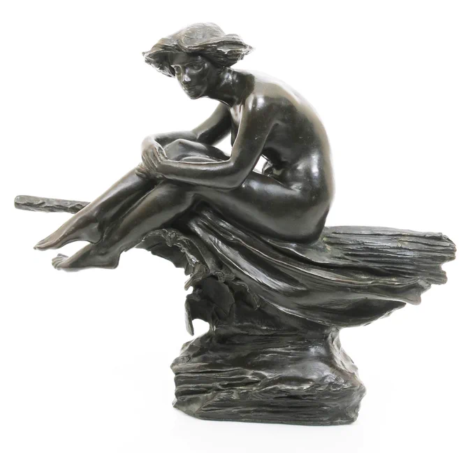 a bronze art deco sculpture of a young woman with wild bobbed hair, flying side saddle on a broom. The figure is naked and clutching her knees in a relaxes way. 
Image from Woolley and Wallis Salisbury Salerooms Ltd., CC BY-SA 4.0 <https://creativecommons.org/licenses/by-sa/4.0>, via Wikimedia Commons
