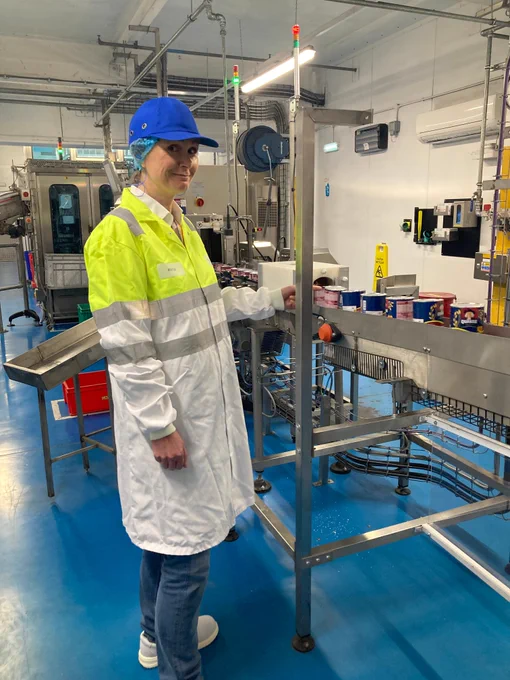 Wendy in the Quaker Oats factory wearing a protective coat, hat and hair net.
