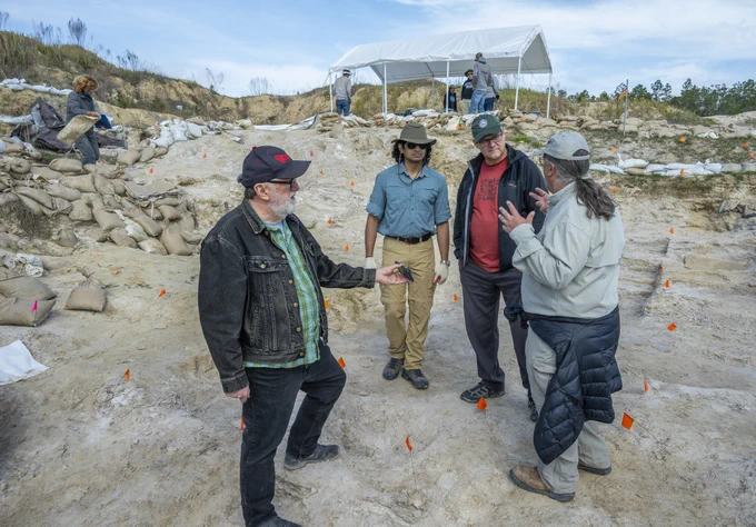 four people are standing in a pit fortified with sand bags talking