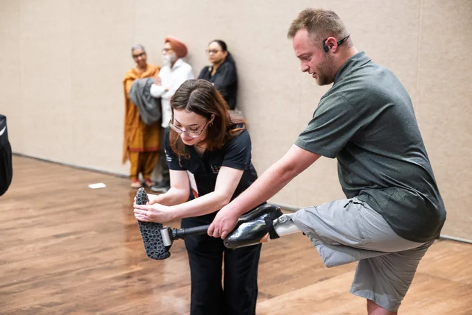 A student helps put prosthetic foot on a fellow student.
