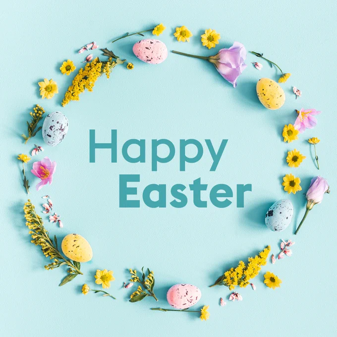 A turquoise background with Happy Easter written in the middle. Surrounding the text is a ring of yellow, pink and lilac flowers and mini chocolate eggs