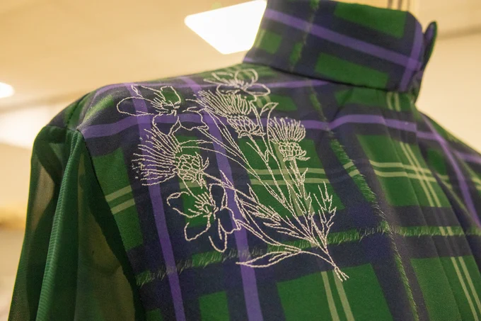 A detail of Kayleigh’s tartan, with embroidered thistle and white jasmine motifs.