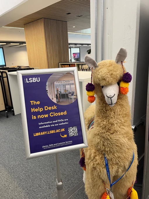 Photo of Rosie the LSBU Library Llama with a poster in a poster holder. Poster reads: The Help Desk is now Closed. Information and FAQs are available via our website library.lsbu.ac.uk