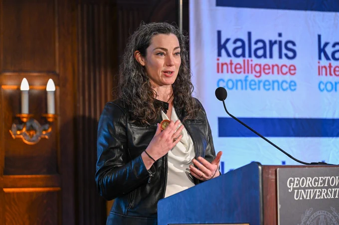 A person is speaking at the Kalaris Intelligence Conference at Georgetown University, standing behind a podium with the event's logos displayed in the background.