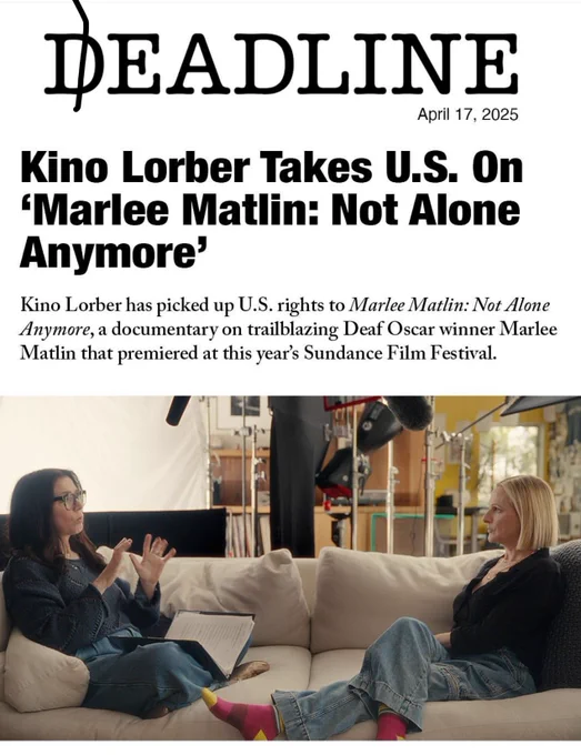 Actress/director, Shoshannah Stern, dressed a dark blouse and jeans with a book in her lap, sits on a couch across from  actress Marlee Matlin, also in a dark blouse and jeans with colored socks and no shoes, while conversing in American Sign Language. The photo is of a headline  dated April 17, 2025,from Deadline stating "Kino Lorber Takes U.S. on "Marlee Matlin: Not Alone Anymore" with a byline, "Kino Lorber has picked up U.S. rights to Marlee Matlin Not Alone Anymore, a documentary on trailblazing Deaf Oscar winner Marlee Matlin that premiered at this year's Sundance Film Festival 