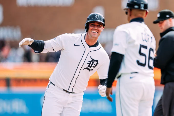 Kerry Carpenter smiles and high-fives third base coach Joey Cora as he rounds the bases after hitting a home run.