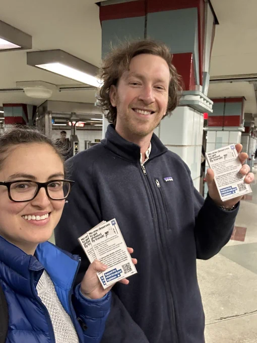 Lena & Karsten smile in the Cta red line lake station vestibule holding palm cards about transit