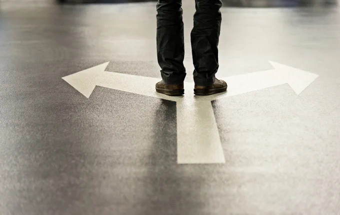 A person stood on an arrow pointing both left and right.