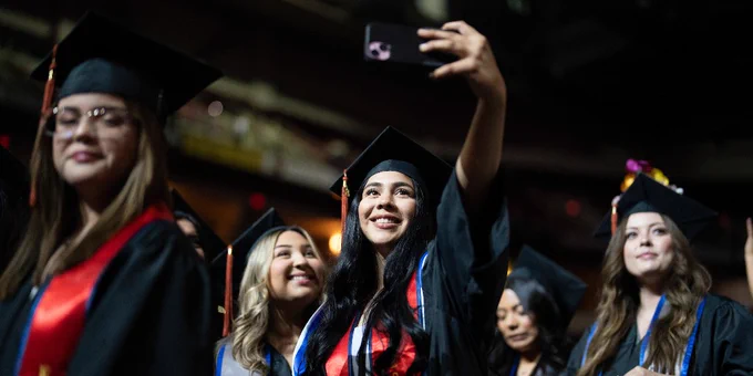 Two Fresno State graduates pose for a selfie during commencement