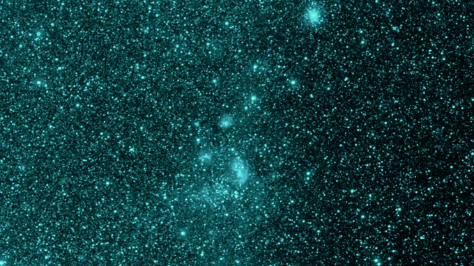A portion of the sky is shown in an infrared wavelength similar to the color teal. This was captured by the SPHEREx space telescope as it scanned the sky and began its science operations. The portion of sky is dotted with hundreds of thousands of various sized stars and galaxies.