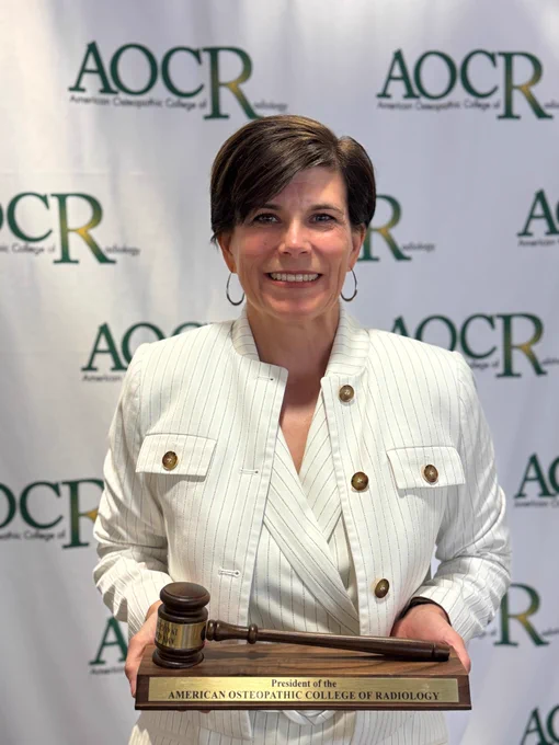 Woman standing proudly showing her award with a smile.