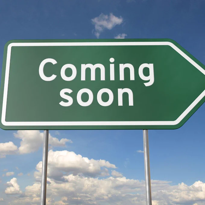 Coming soon green and white road sign.  Blue sky with white clouds.