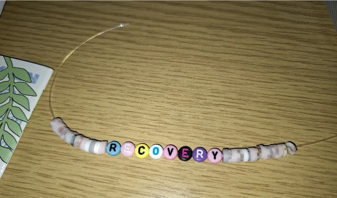 hand-made bracelet with colourful beads in the middle spelling 'recovery'