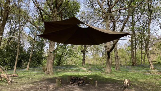 A canvas canopy stretched over a seating area in the Slung Low Woods