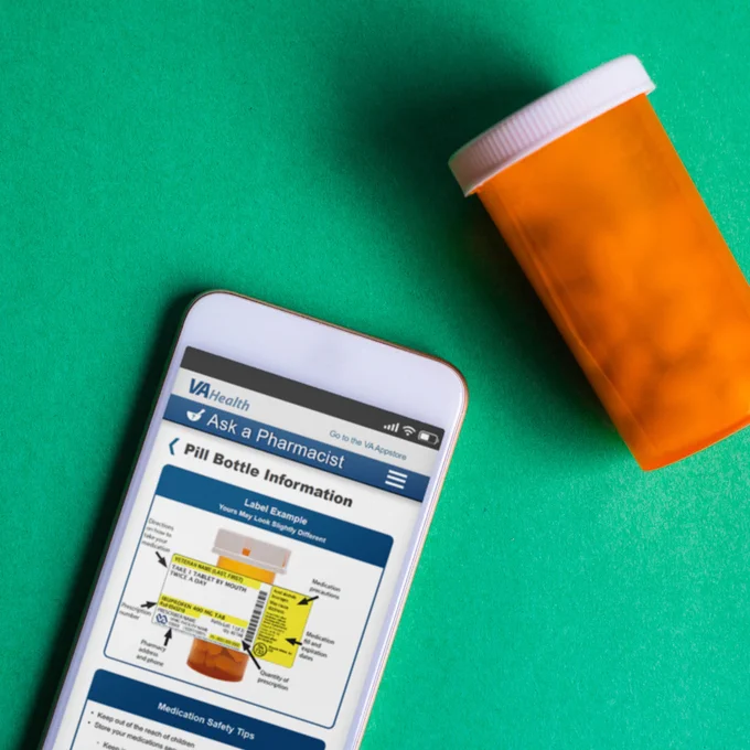 A cell phone and an orange prescription bottle on a green background with the Ask a Pharmacist app open on the cell phone’s browser.

