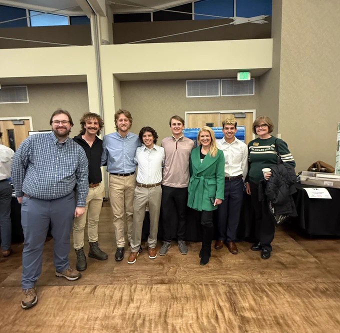 President Amy Parsons stands with a group of students, faculty and staff during E-Days. They are gathered in front of student project displays inside the LSC.