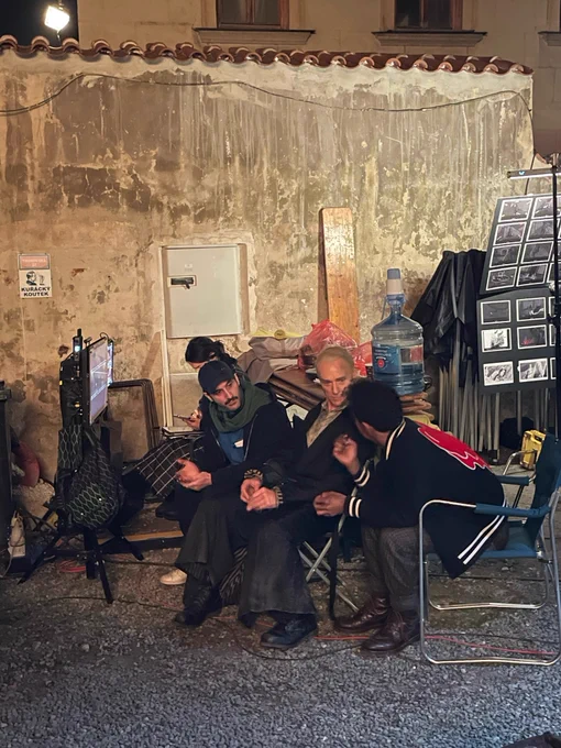 Jacob Anderson, in his own clothes, sits in a chair, leaning over, his head turned as he talks to Ben Daniels, in costume as Santiago, next to him. Director Levan Akin sits on a chair on the opposite side of Ben Daniels, leaning over and intently listening to Jacob. The storyboards for the scene are displayed on the right, above Jacob’s back. 