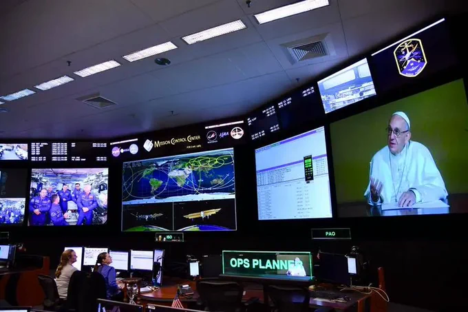 On a screen at right in NASA’s Mission Control Center in Houston, Pope Francis speaks to the crew aboard the International Space Station on Oct. 26, 2017. Credit: NASA
