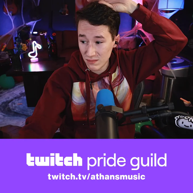 A photo of me, Athan, making a confused/grossed out face wearing a maroon Limbo Hoodie (my album, a painting of Icarus) - the text "Twitch Pride Guild" and "twitch.tv/athansmusic" written below.
