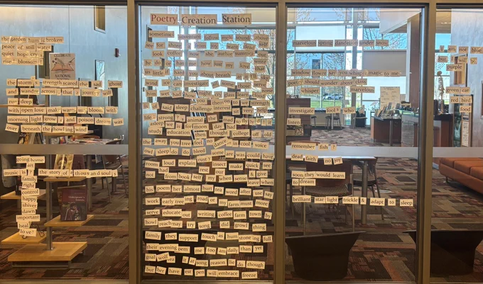Poetry creation station with laminated individual words taped to a large window. Passersby have rearranged some of the words to create different poetry compositions.