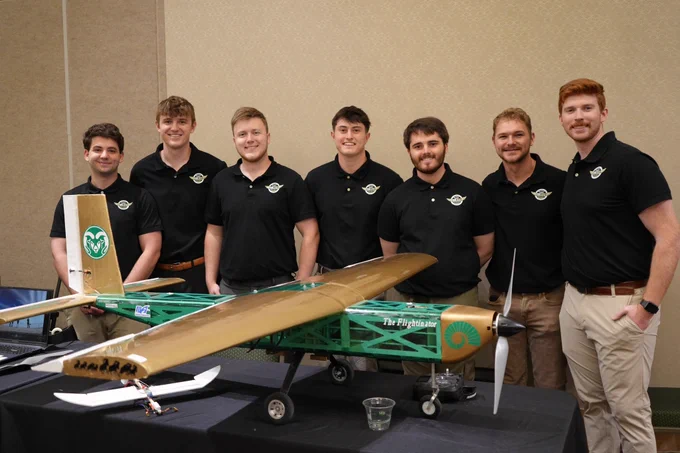 A group of students posing behind a plane.