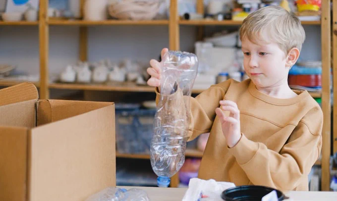 Young child sorting plastic bottles for recycling, promoting eco-friendly habits.