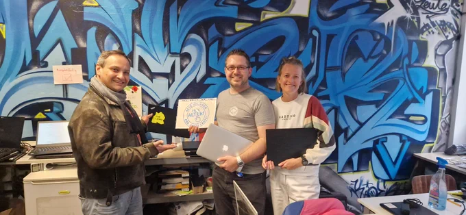 Eine Gruppe von Leuten hält Laptops und lächelt.