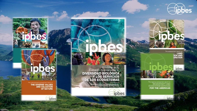 Composite image showing four IPBES assessment report covers arranged over a scenic mountain landscape background with blue sky and white clouds. The central report cover, in Spanish, focuses on "Biodiversidad Biológica y los Servicios de los Ecosistemas" with turquoise marine imagery. To the left, an orange-colored report on "The Diverse Values and Nature" features cultural and wildlife photos. To the right, a green-themed report covers "Biodiversity and Ecosystem Services for the Americas." Each cover displays the IPBES logo and contains small photographic elements showing nature, wildlife, and local communities. The mountain backdrop features lush green slopes and a water body. The IPBES logo appears in the top right corner of the overall image.