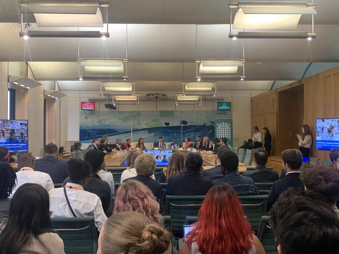 A panel of 13 politicians, student leaders, and experts being watched by a group of 50 student officers in a room in parliament