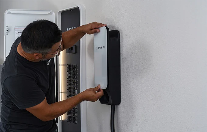 Person installing a SPAN smart electrical panel on a wall.