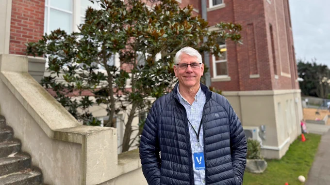 Marc Fairbanks stands outside Lowell with a visitor badge