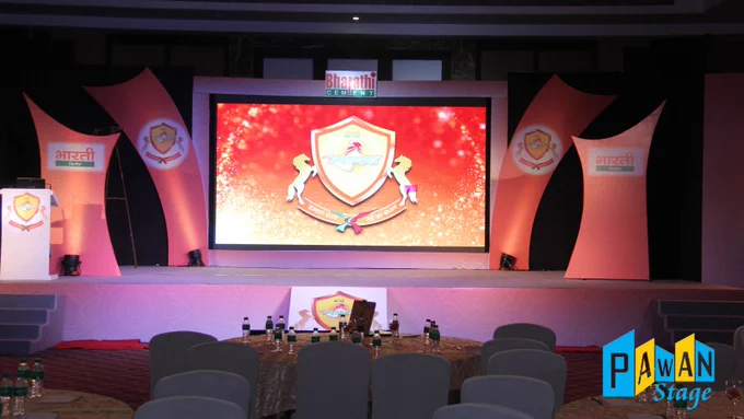 Stage set for the Bharathi Cement product launch at banquet hall in Udaipur, featuring elegant table arrangements and stage decor.
