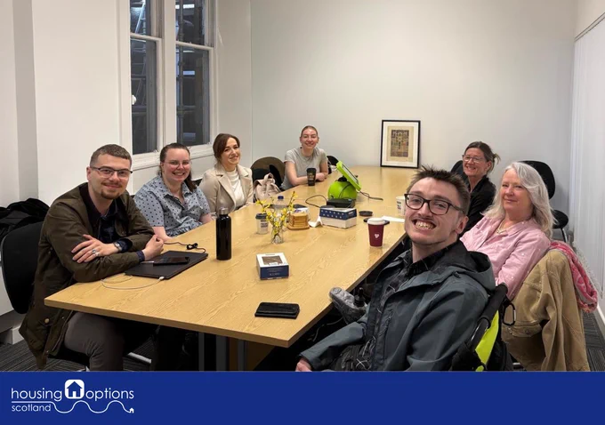 A group of people sat around a table smiling at the camera