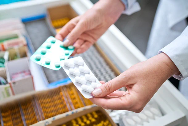A person holds two packs of pills
