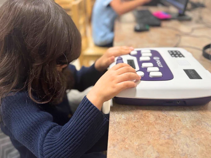 (Photo) Miami Lighthouse Academy student practices braille with a smart brailler device, which encourages multi-sensory learning through visual, tactile and auditory feedback.