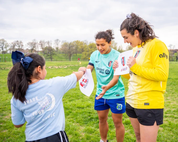 Laurel and Rocky receiving art work from a Girls on the Run participant