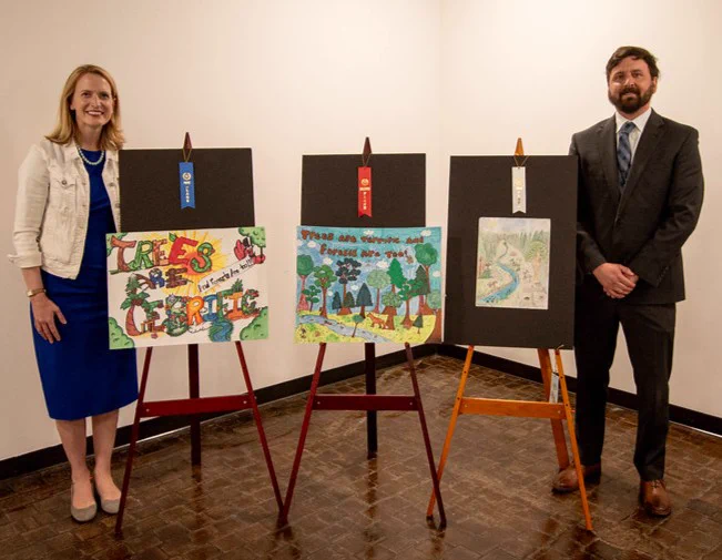 State Comptroller Brooke Lierman and Department of Natural Resources Secretary Josh Kurtz stand with the top three winning entries of the 2025 Maryland Fifth Grade Arbor Day Poster contest.