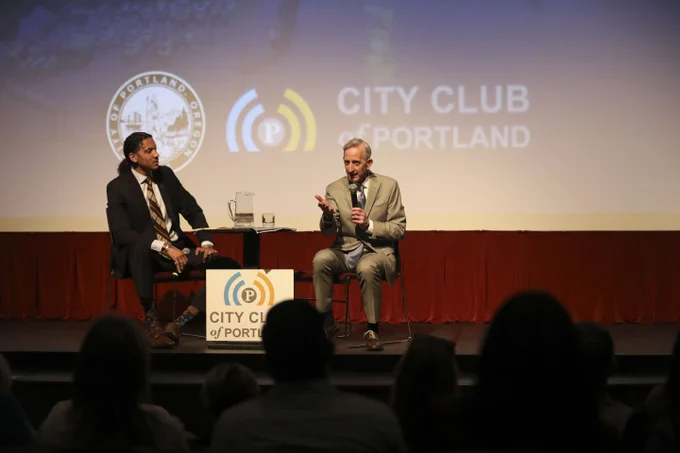 Mayor Wilson and JT Flowers sitting on the stage at Franklin High School having a conversation during the State of the City event, while Mayor Wilson gestures at the crowd